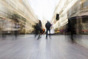 Pessoa em meio à multidão borrada, representando o cansaço constante da rotina acelerada
